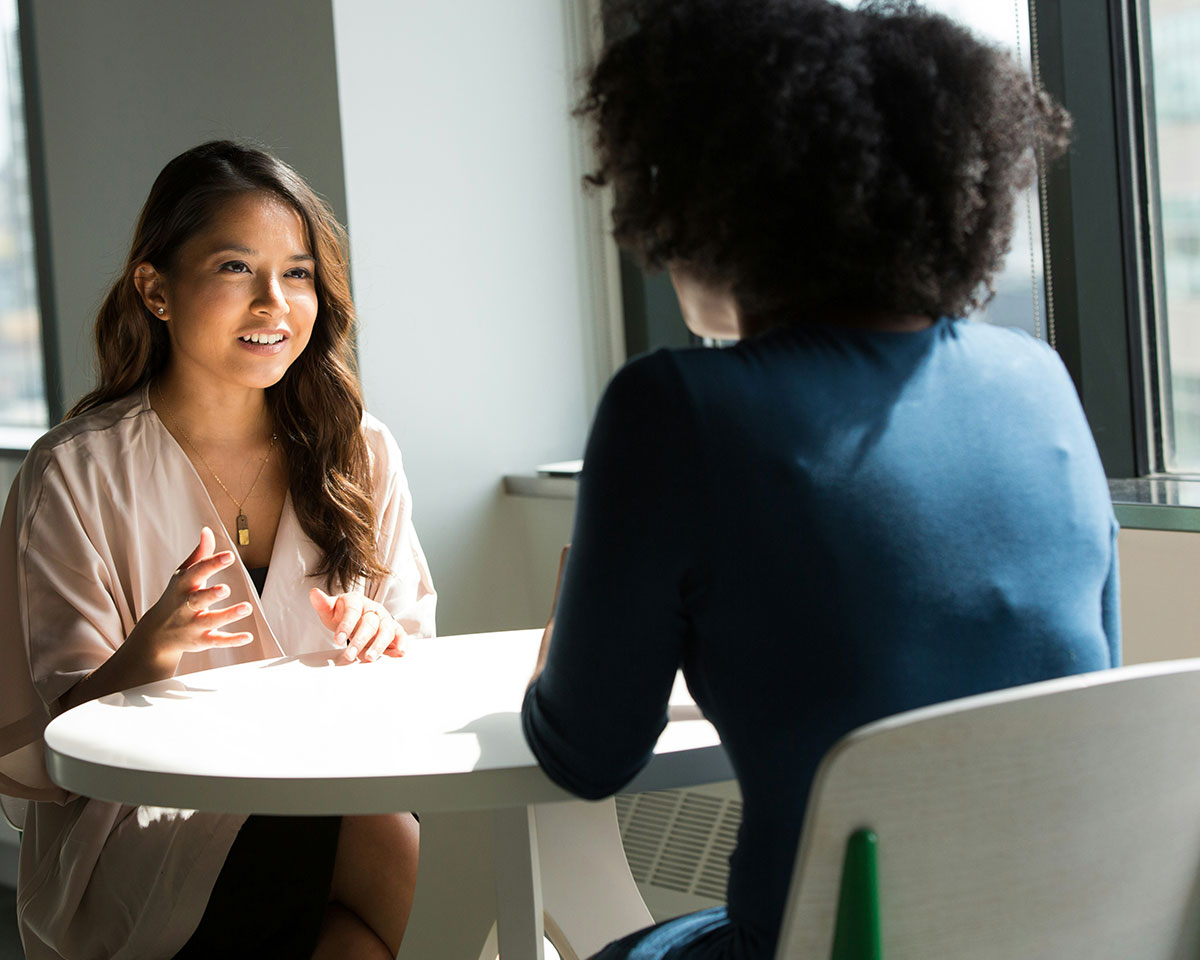 two women talking over a table during affordable therapy session