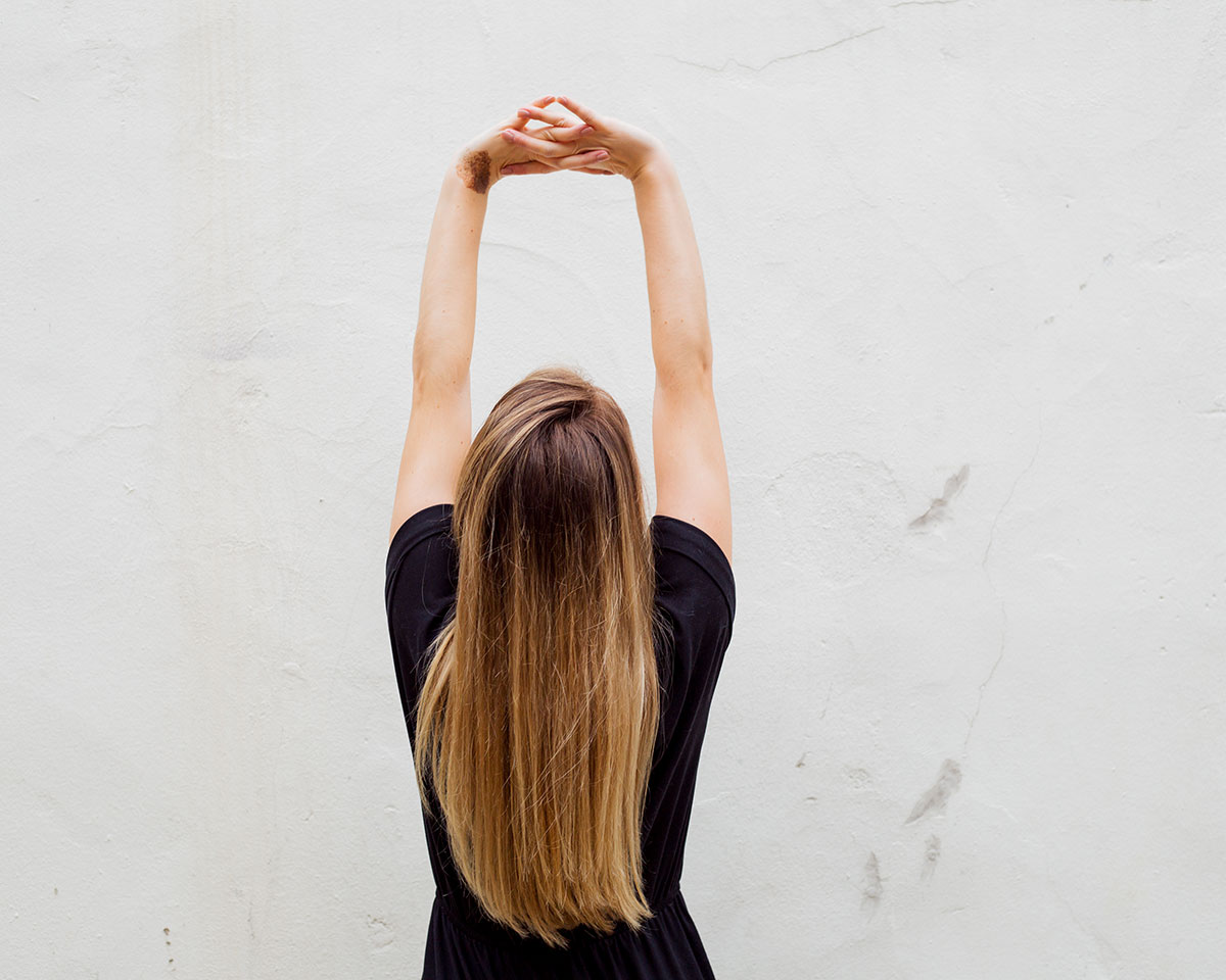 back of woman stretching arms overhead as part of somatic therapy practice