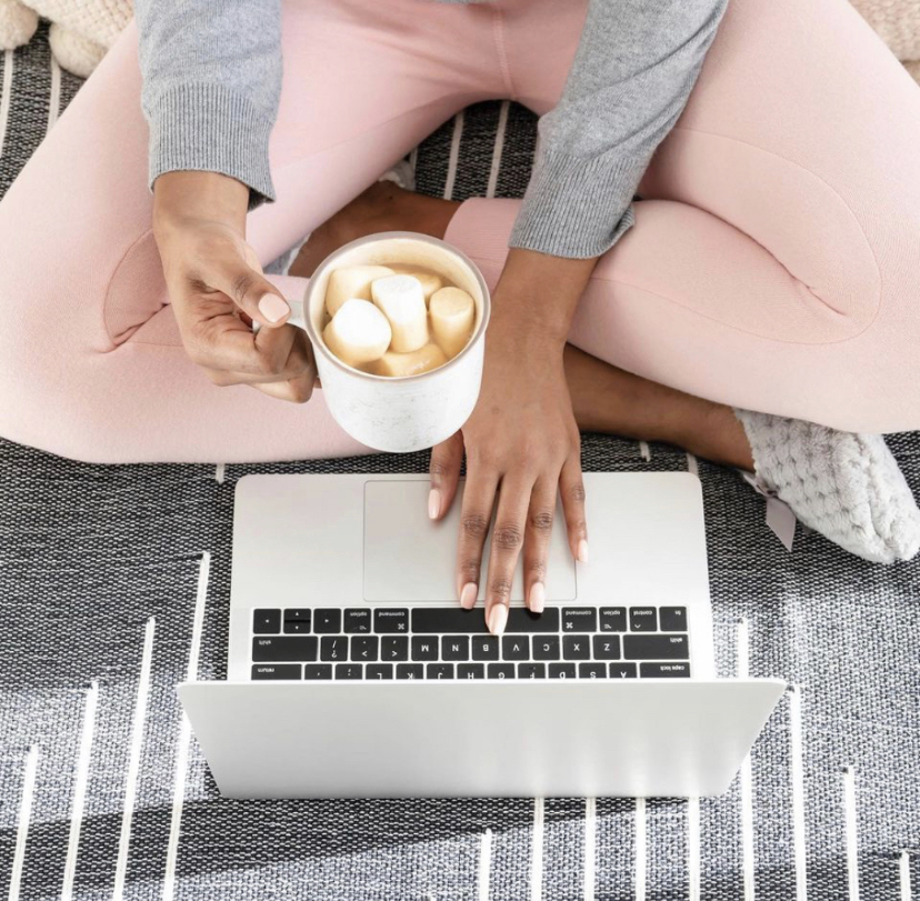 A woman is drinking hot chocolate and working from home on her laptop
