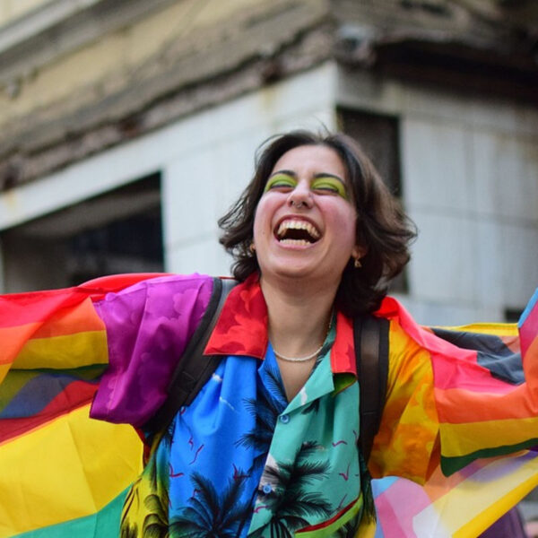 person at bride wearing rainbow palm tree top and carrying flag, for post on how to be a better ally