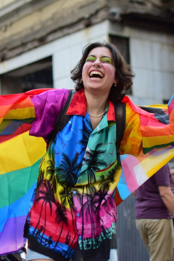 person at bride wearing rainbow palm tree top and carrying flag, for post on how to be a better ally