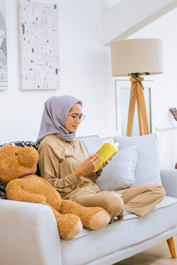 photo of woman on couch reading book engaging in self care