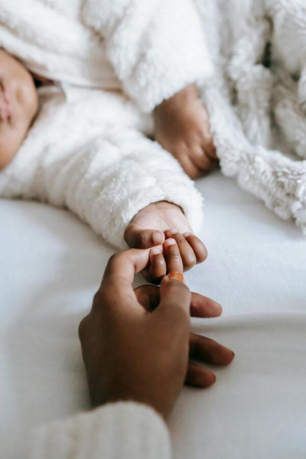 image of mothers hand holding childs hand for article on postpartum anxiety