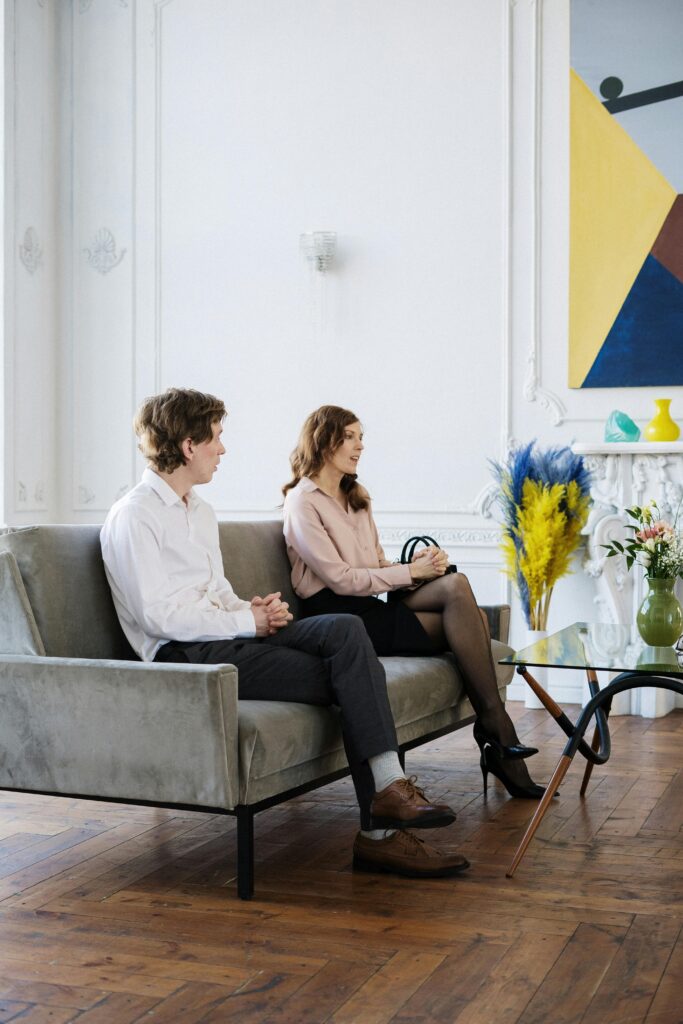 a man and woman who are engaged sit on a couch for pre-marital counseling