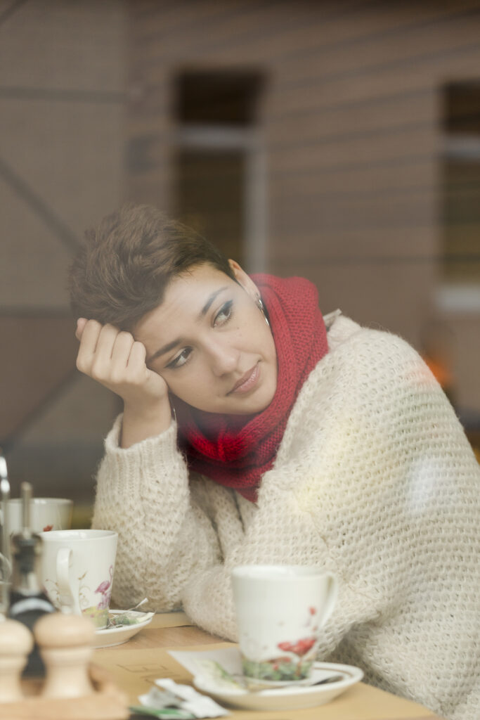 woman with short hearing wearing a red scarf in a coffee shop in Philadelphia struggling with Seasonal Affective Disorder 