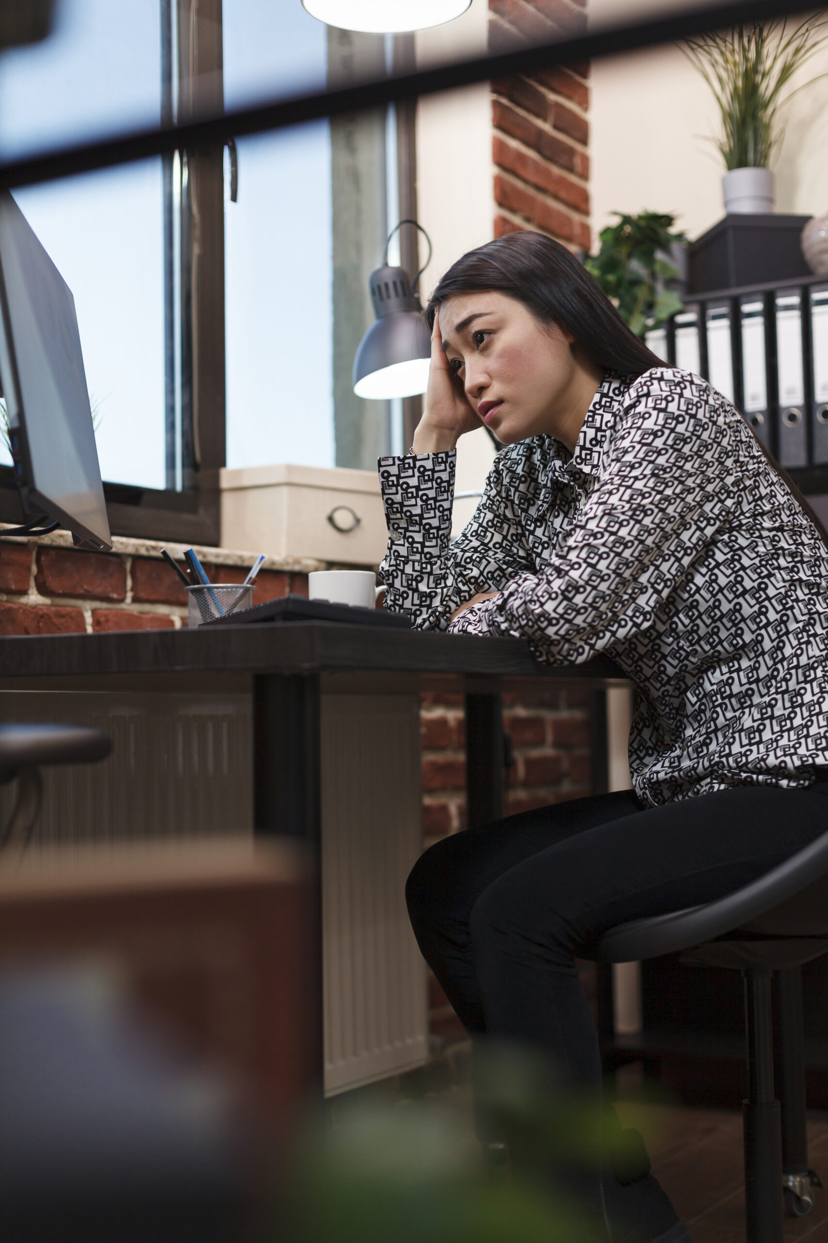 woman with head in hands at office desk