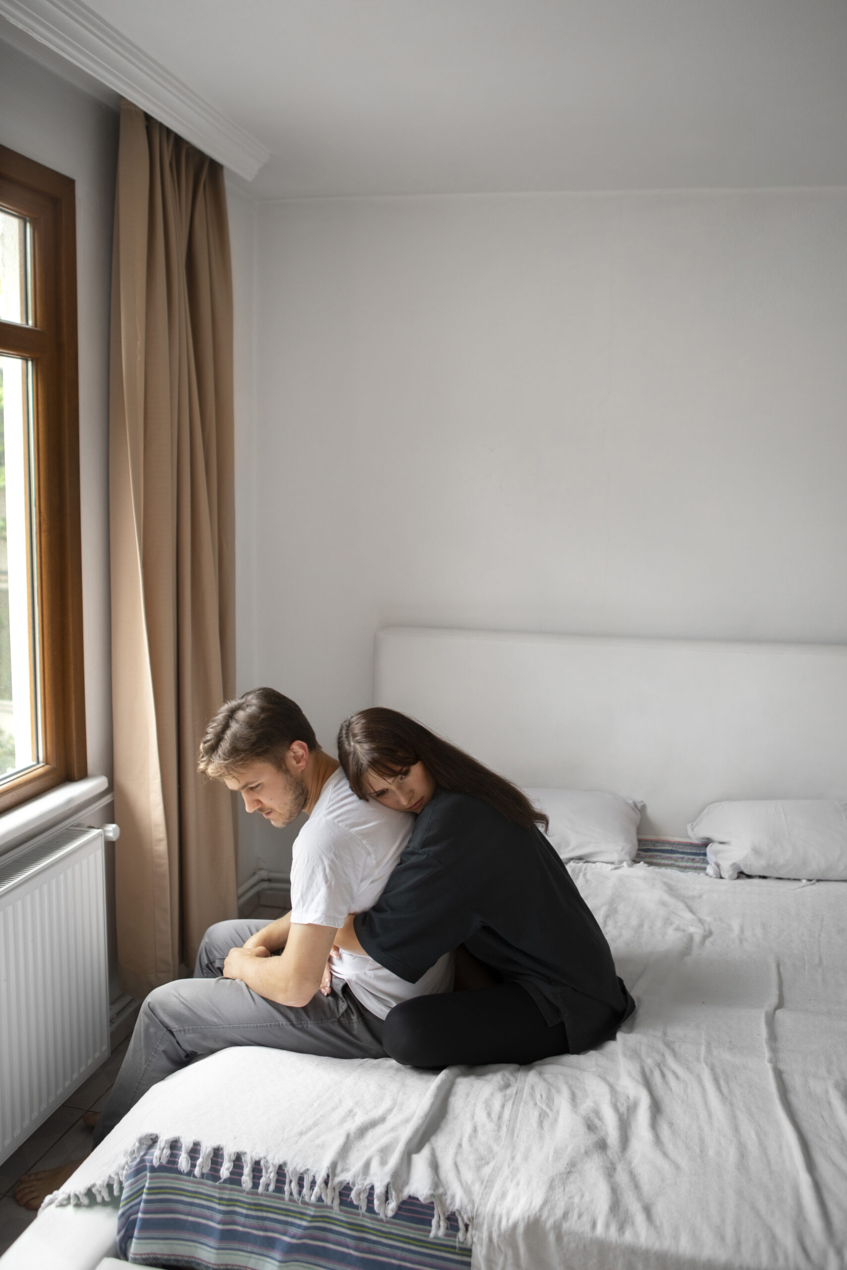 couple sitting on a bed feeling sad because they are considering parental estrangement