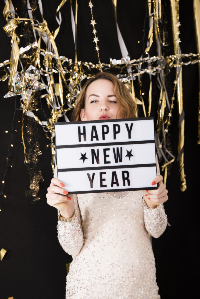 woman holding a sign that says happy new year. People will ask "did you quit your new year's resolution?"

