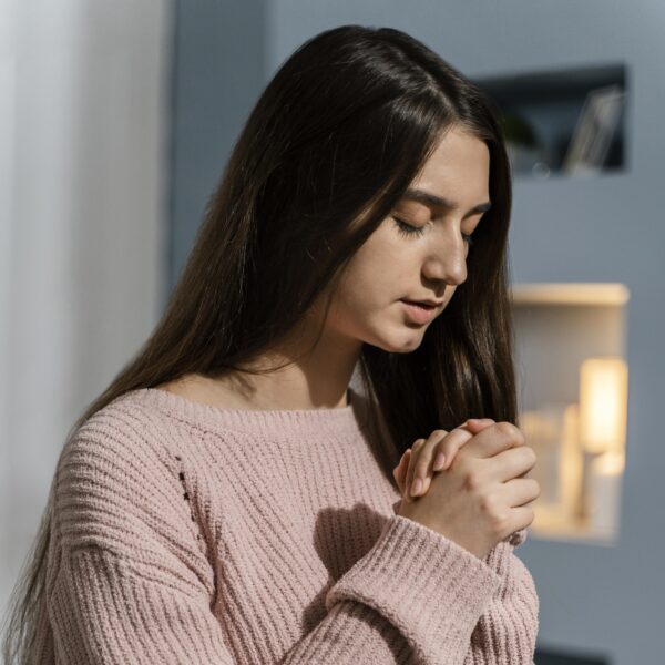 woman in black hair and pink sweater praying due to OCD Scrupulosity