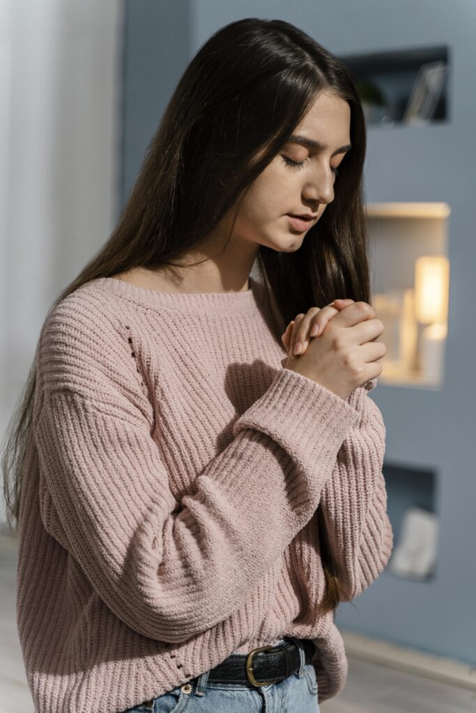 woman with long brown hair in a pink sweater praying due to OCD Scrupulosity