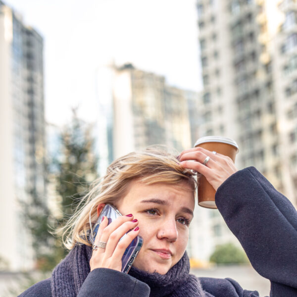 women on phone holding coffee looking stressed