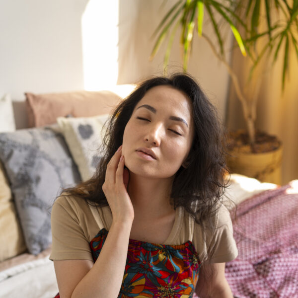 woman sitting on beed with hand on her neck