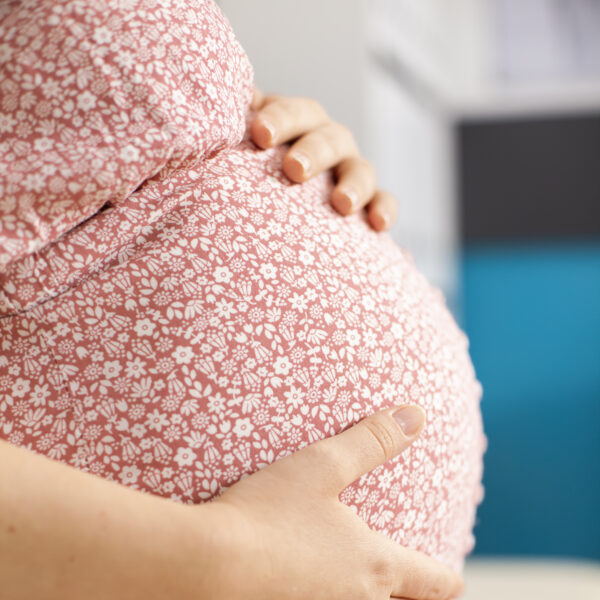 closeup of pregnant woman in dress holding belly