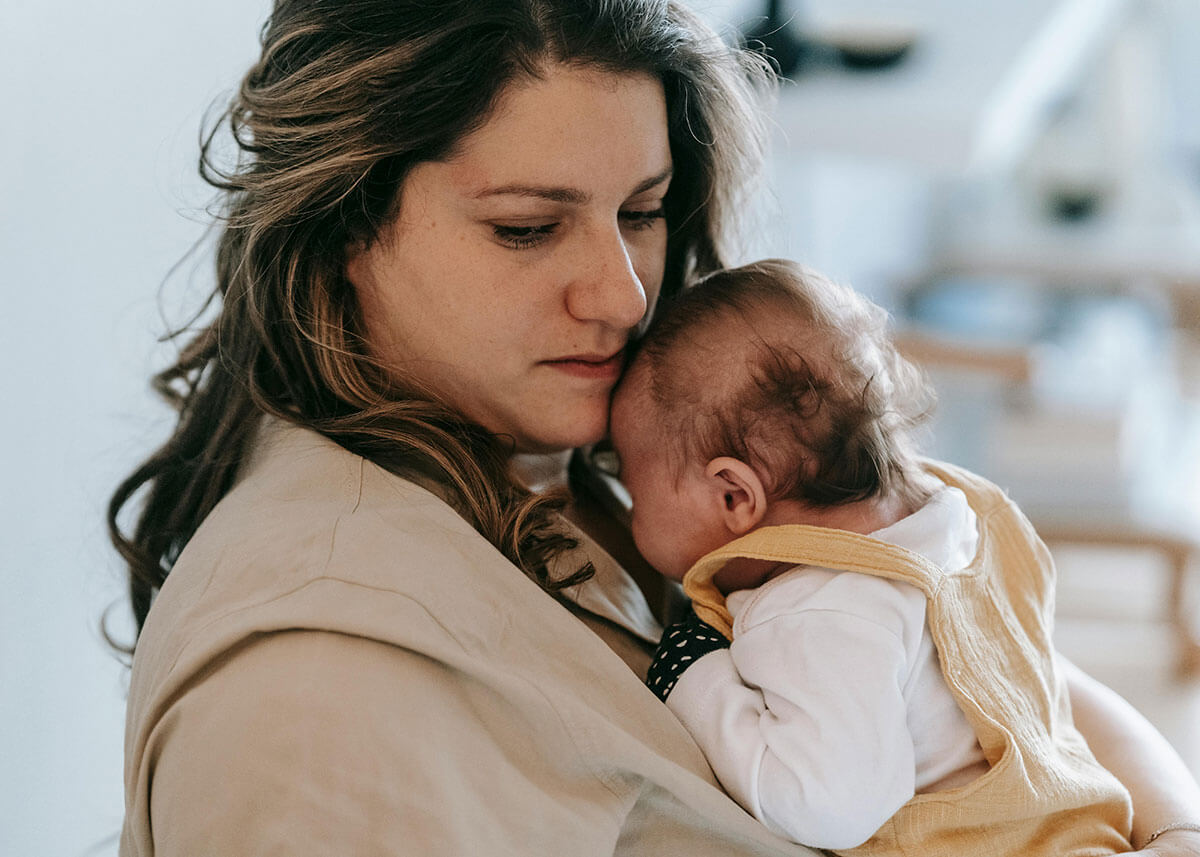 Tired mom holding baby for page on perinatal mental health therapy