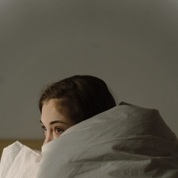 woman hiding in blanket covers with anxiety about sleep