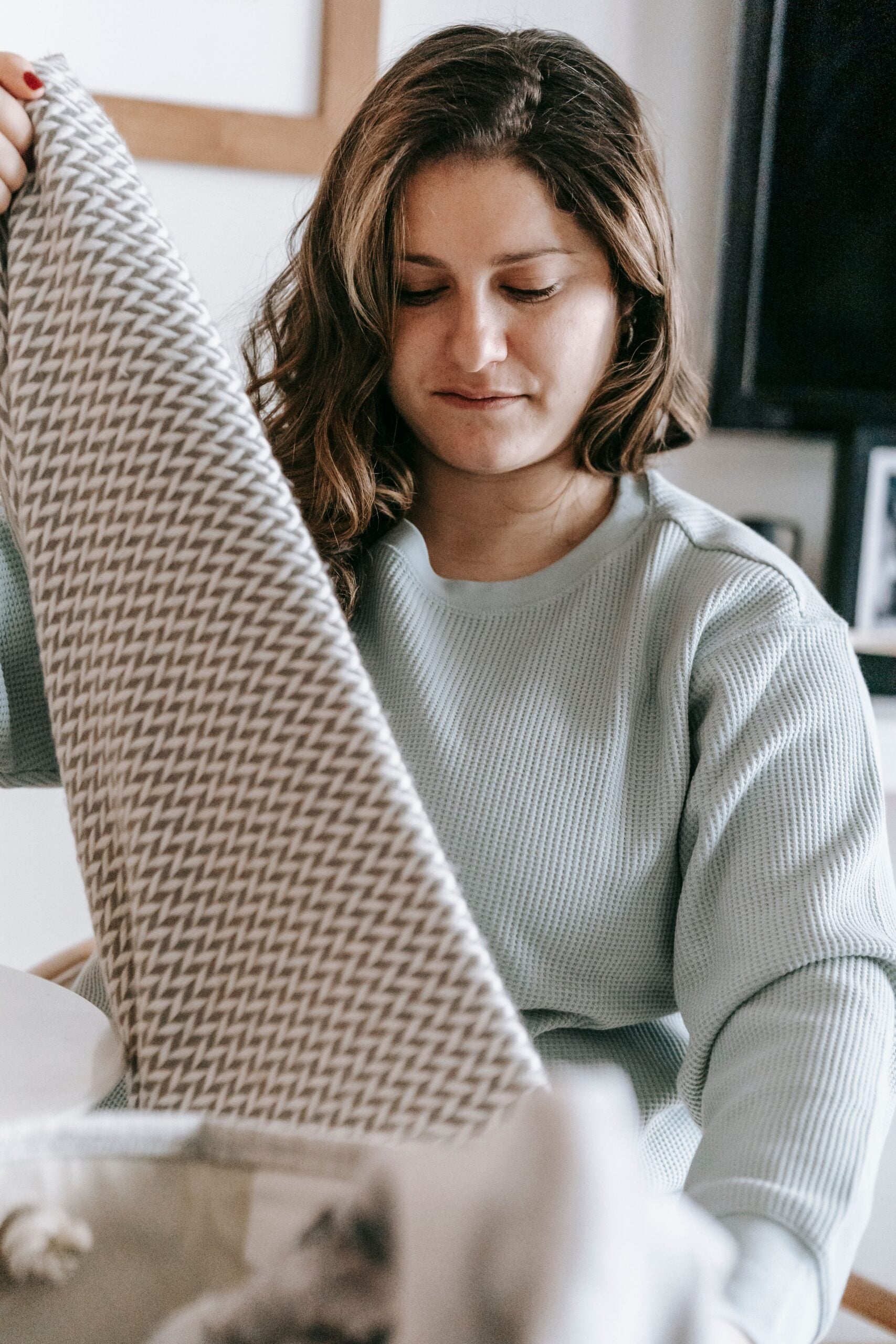 Mom struggling with postpartum OCD, folding a blanket